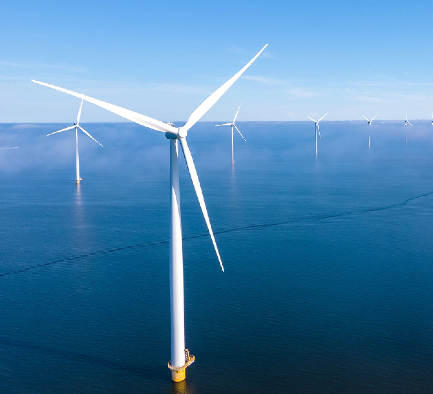 A wind turbine standing in the sea with others stood in the background